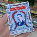 Wangwan Medicated Oil: The Best Roll-On for Pain at 7-Eleven Thailand Person holding a white sachet of Takabb Anti-Cough Pills with centipede illustrations in a Thailand 7-Eleven