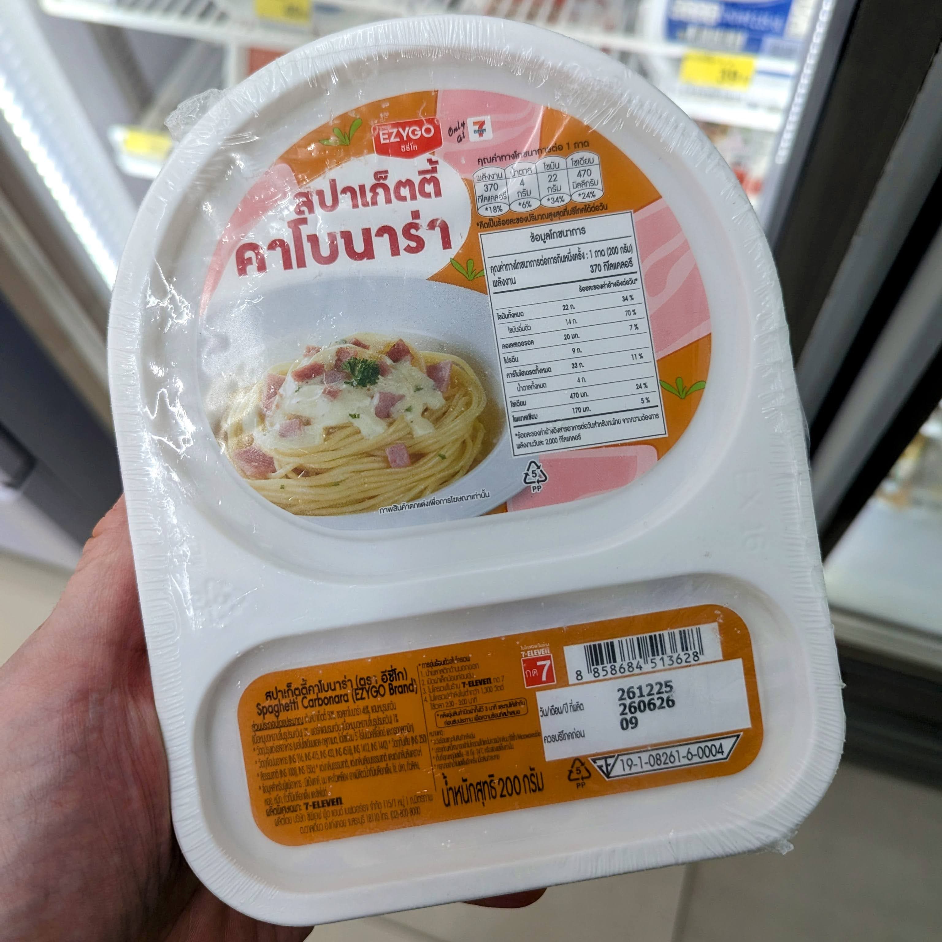 A tray of 7-Eleven Thailand Carbonara spaghetti with a critical review rating.