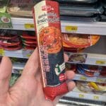 A person holding a packaged Ezygo Hot Gimbap Roll with stir-fried pork and kimchi from 7-Eleven Thailand.