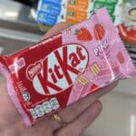 Ezygo Hot Gimbap Roll Review: Stir-Fried Pork & Kimchi Flavor A person holding a KitKat Pink Strawberry chocolate bar from 7-Eleven Thailand.