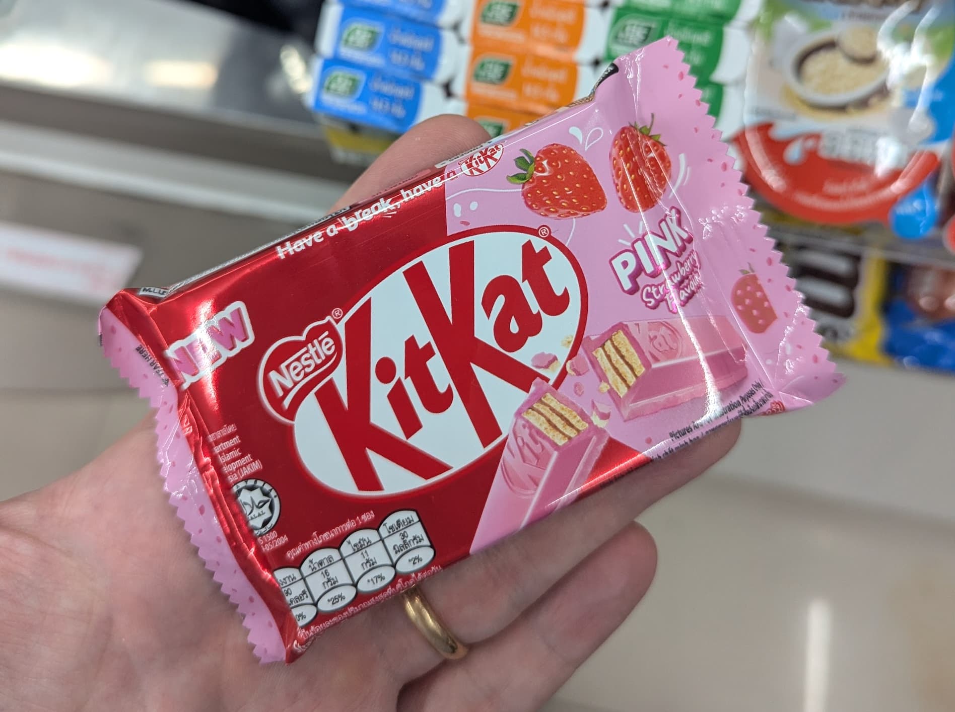 A person holding a KitKat Pink Strawberry chocolate bar from 7-Eleven Thailand.