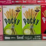Vaseline Gluta-Hya Review: The Viral Thai Skincare Secret Every Traveler Needs A box of Glico Pocky Milky Matcha being held against a bright 7-Eleven background in Thailand.