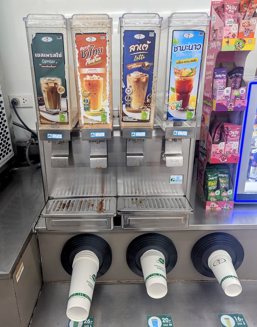 A row of self-serve drink dispensers at 7-Eleven Thailand featuring Espresso, Thai Tea, Latte, and Nestea Lemon.