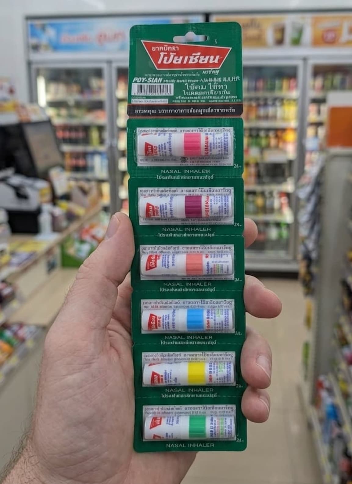 A display of Poy-Sian Mark II nasal inhalers in various colors at a 7-Eleven in Thailand.