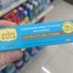 A hand holding a blue box of Tepthai Concentrated Herbal Toothpaste in a 7-Eleven Thailand aisle.