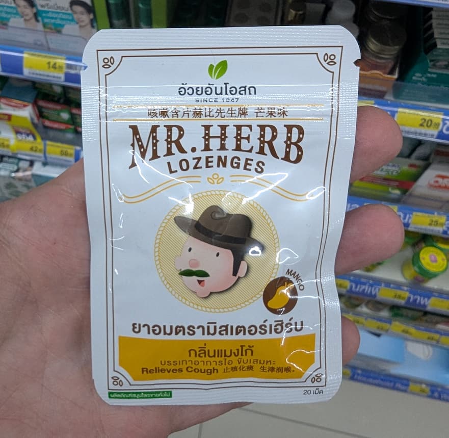 A white resealable pouch of MR.HERB Mango Lozenges from a 7-Eleven in Thailand, recommended for cough relief.
