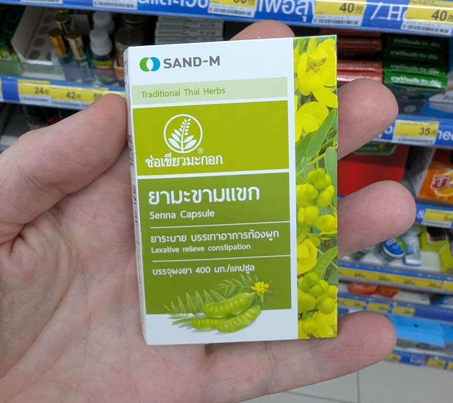 A box of SAND-M Senna Capsules from a 7-Eleven in Thailand, used for constipation relief while traveling.