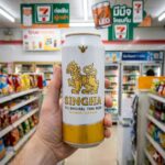 A 490ml gold can of Singha Beer featuring the mythical lion logo from a 7-Eleven in Thailand.