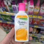 Aura 100% Natural Mineral Water: Why This Green Cap Dominates the Water Aisle A white bottle of Soffell Mosquito Repellent Lotion with a pink cap held inside a 7-Eleven store in Thailand.