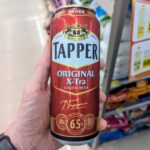 Ezy Taste Sausage Cheese Sandwich: A High-Value Crowd-Pleaser with Better Rivals A hand holding a red and silver tall boy can of Tapper Original X-Tra lager beer inside a store in Thailand.
