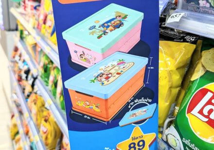 A blue vertical promotional display sign for the 7-Eleven ALL Member Crayon Shin-chan collapsible storage boxes on a store shelf in Thailand.