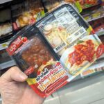 A white plastic tray of Ezygo Spaghetti with chicken in tomato sauce and sausage from 7-Eleven Thailand.