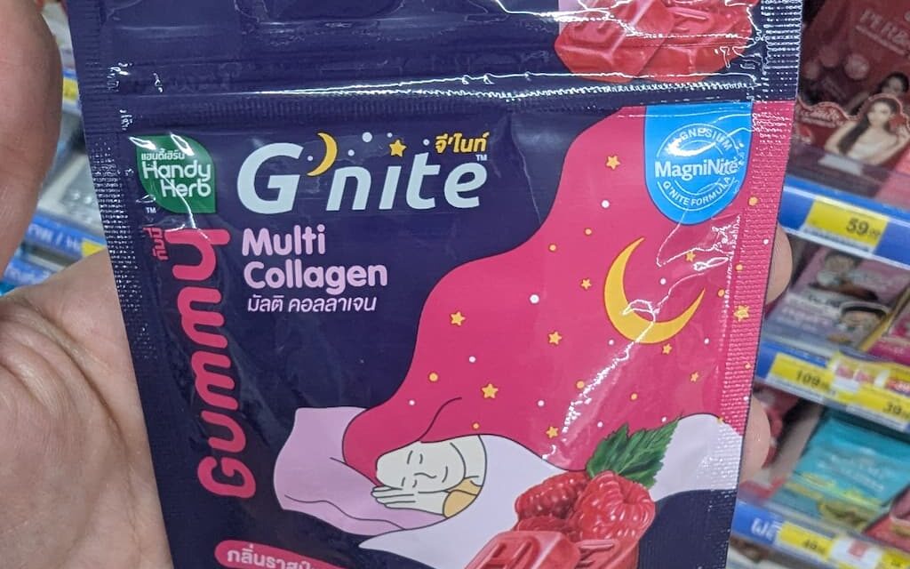 A hand holding a purple and pink sachet packet of HandyHerb G'nite Multi Collagen Gummy inside a store in Thailand.
