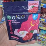 A hand holding a purple and pink sachet packet of HandyHerb G'nite Multi Collagen Gummy inside a store in Thailand.