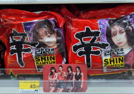 Nongshim Shin Ramyun Aespa Edition: The Undisputed King of Korean Instant Noodles Red packaging packets of Nongshim Shin Ramyun instant noodles featuring Aespa members on a 7-Eleven store shelf in Thailand.