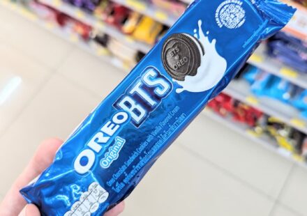 Oreo Original BTS Edition: The Same Classic Cookie Wrapped in Global Pop Hype A hand holding a blue metallic plastic tube packaging of limited edition Oreo Original BTS cookies inside a store in Thailand.