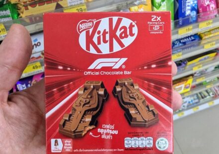 KitKat F1 Official Chocolate Bar: An Elite Racing-Themed Novelty That Delivers Outstanding Flavor A hand holding a red box of KitKat F1 Official Chocolate Bar featuring two molded chocolate racing cars inside a 7-Eleven in Thailand.