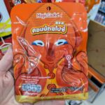 A hand holding an orange pouch of Magic Cook Konjac Spicy Flavour by Haidilao featuring a cartoon octopus inside a 7-Eleven in Thailand.