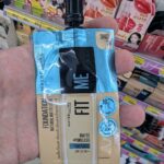 A hand holding a Maybelline Fit Me Matte + Poreless Foundation sachet in Shade 128 inside a 7-Eleven store in Thailand.