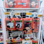 A white display rack filled with red box Monchhichi x Amaze One power banks and tech accessories inside a 7-Eleven store in Thailand.