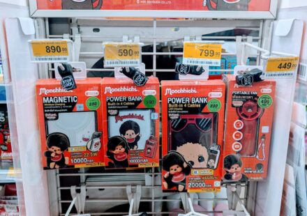 A white display rack filled with red box Monchhichi x Amaze One power banks and tech accessories inside a 7-Eleven store in Thailand.