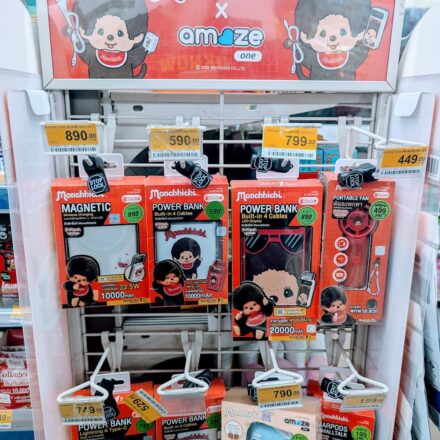 A white display rack filled with red box Monchhichi x Amaze One power banks and tech accessories inside a 7-Eleven store in Thailand.