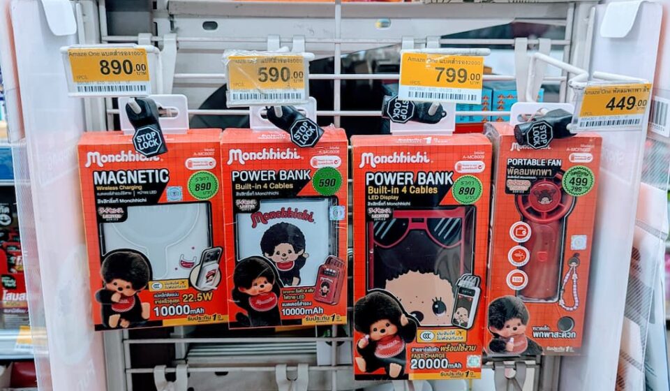 Monchhichi x Amaze One Tech Accessories: Flashy Character Power Banks and Gadgets with Niche Appeal A white display rack filled with red box Monchhichi x Amaze One power banks and tech accessories inside a 7-Eleven store in Thailand.