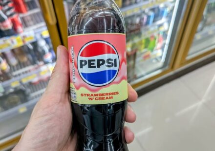Pepsi Strawberries ‘N’ Cream Zero Sugar: A Bold Dessert Fusion Limited by Overwhelming Sweetness A hand holding a clear plastic bottle of Pepsi Strawberries 'N' Cream Zero Sugar soda with a pink cap inside a 7-Eleven store in Thailand.