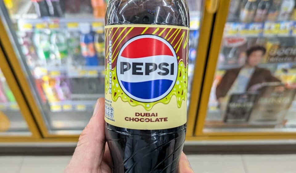 Pepsi Zero Sugar Dubai Chocolate: A Viral Flavor Mashup That Tests the Limits of Flavored Cola A hand holding a green-capped bottle of Pepsi Zero Sugar Dubai Chocolate flavor inside a 7-Eleven store in Thailand.