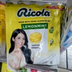A yellow hanging plastic pouch of limited edition Ricola Lemonmint sugar-free candy featuring K-pop idol IU on a store shelf in Thailand.