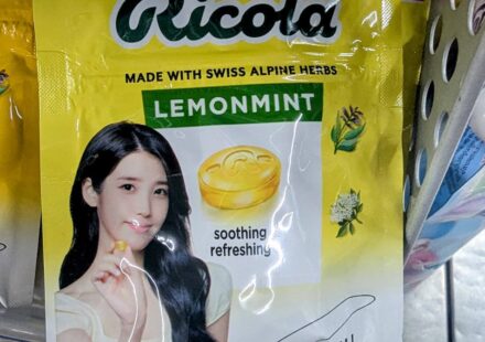 A yellow hanging plastic pouch of limited edition Ricola Lemonmint sugar-free candy featuring K-pop idol IU on a store shelf in Thailand.