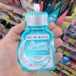 The Ultimate Guide to Local Thai Beers at 7-Eleven: Complete List & ABV Breakdown A hand holding a turquoise pouch of Rojukiss Reju-PDRN Sleeping Mask inside a 7-Eleven store in Thailand.