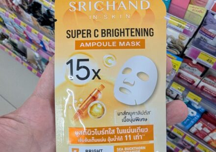 A hand holding a yellow sachet of Srichand In-Skin Super C Brightening Ampoule Mask inside a 7-Eleven store in Thailand.