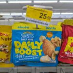 Pocari Sweat Ion Supply Drink: Essential Hydration for Tropical Heat & Post-Illness Recovery A hand holding a blue pouch of Sunbites Daily Nuts Daily Boost 5 in 1 hanging on a 7-Eleven rack in Thailand with a 25 THB price tag above.