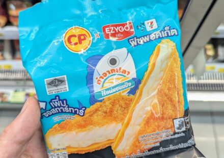 CP x Ezygo Fish Pocket: A Breadless, Tartar-Packed Crispy Fish Treat at 7-Eleven A hand holding a cyan-blue package of CP x Ezygo Fish Pocket inside a 7-Eleven store in Thailand.