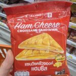 Vitamilk Double Black Sesame & Black Rice: Nutrient-Dense Plant Milk with a Satisfying Roasted Flavor A hand holding a red package of Ezygo Ham Cheese Croissant Sandwich inside a 7-Eleven in Thailand.