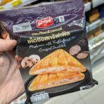 7-Eleven Thailand Monchhichi Stamp Promotion 2026: Complete Premium Collectibles & Expat Redemption Guide A hand holding a black package of Ezygo Mushroom with Truffle Sauce Croissant Sandwich inside a 7-Eleven store in Thailand.