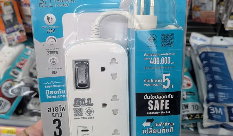 BLL B54 Power Strip Extension (3M): A Reliable, Safe Travel Lifesaver at 7-Eleven Thailand A hand holding a blister pack of BLL B54 High Quality Power Strip inside a 7-Eleven store in Thailand.