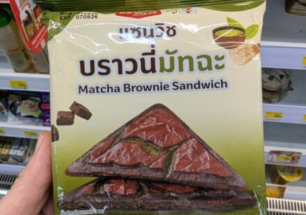 Ezygo Matcha Brownie Sandwich: A Hot, Surprise Sweet Toastie with Balanced Green Tea Earthines A hand holding a green and beige package of Ezygo Matcha Brownie Sandwich inside a 7-Eleven store in Thailand.