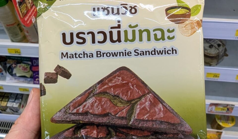 Ezygo Matcha Brownie Sandwich: A Hot, Surprise Sweet Toastie with Balanced Green Tea Earthines A hand holding a green and beige package of Ezygo Matcha Brownie Sandwich inside a 7-Eleven store in Thailand.