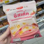 Ezygo Mushroom with Truffle Sauce Croissant Sandwich: A Rich, Gourmet Truffle Indulgence A hand holding a pastel pink package of Ezygo Strawberry Cream Cheese Cheesecake Sandwich inside a 7-Eleven store in Thailand.